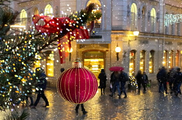 christmas red ball  festive holiday street decoration green tree branch people walk with umbrella evening blurred light medieval city Talluinn old town 