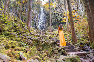 Frau im gelben Kleid vor einem Wasserfall mitten im Schwarzwald