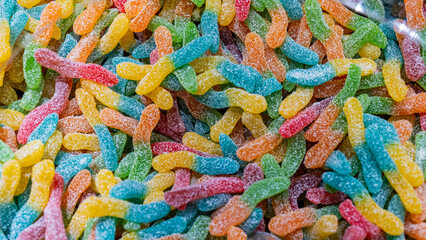A multitude of colorful food sour worms as bombons lying next to each other. Texture of a candy or...