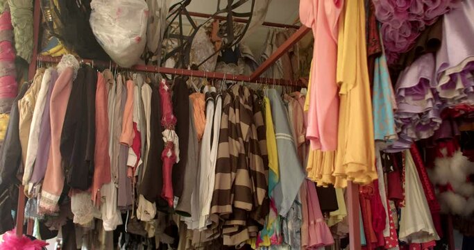 Rack with clothes hangers in the dressing room of the theatre. A lot of multi-colored fabrics on hangers are elements of clothing. Camera movement.