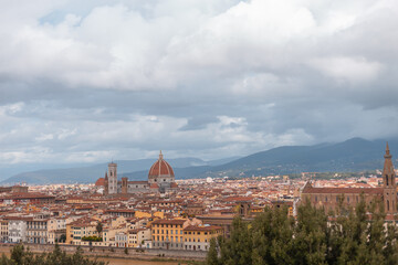 Fototapeta na wymiar Beautiful amazing city with ancient houses and a cathedral in the mountains in Florence, Italy on a cloudy day