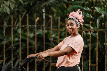 Imagen horizontal de una hermosa y sonriente mujer afroamericana con cabello rosado al aire libre...