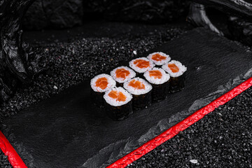 Asian cuisine. Roll with salmon on a black stone on a black background. rice nori salmon