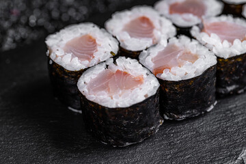 Asian cuisine. Roll with perch on a black stone on a black background. rice nori perch