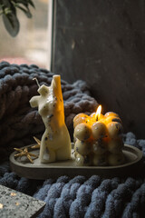 A bubble candle and a white candle shaped as a female body on a concrete tray