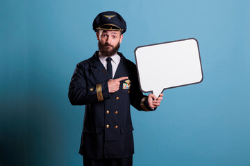 Airplane capitan pointing with finger at white blank speech bubble, communication frame, advertising mock up. Plane pilot holding empty message balloon with place for text