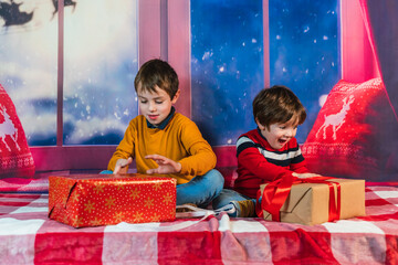 Happy sibling children opening christmas presents together