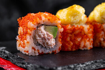Asian cuisine. Rolls Yamagata. Rice nori caviar tobiko crab avocado parmesan on a black background.