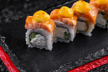 Asian cuisine. Rolls Koti. Rice nori salmon cremette cheese cucumber parmesan on a black background.
