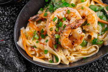 Wok shrimp in coconut milk in a plate on a black background