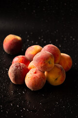 Fototapeta na wymiar Fresh ripe juicy whole and cut red peaches on rough black background.