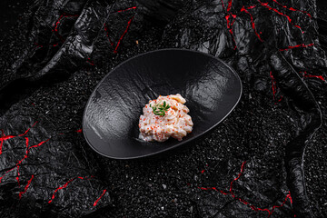 Asian cuisine. Perch salad in a black plate on a black background.
