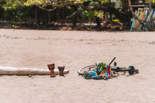 Imagen de tambores y una bicicleta con mantas coloridas sobre la arena de la playa en un día soleado del caribe de Costa Rica 