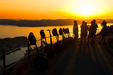 Beautiful landscape, group of tourists, segways and sunset seen from the Mount Floyen in Bergen in...