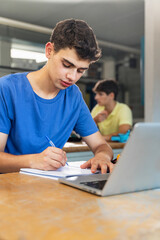 Young boy student writing exercise in the college technology classroom