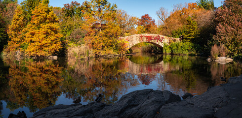 Herbst am Teich im Central Park mit Reflexion von Herbstlaub und Gapstow Bridge. Manhattan, New York City