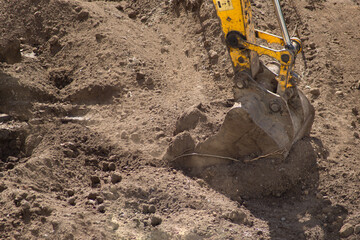 Excavator at the construction site during earthworks. Excavator bucket with earth close-up. Earthworks at a construction site.
