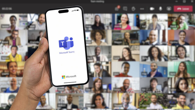 Boy holding a smartphone iPhone 14 Pro with Microsoft Teams app on the screen. Online meeting participants blurred in the background. Rio de Janeiro, RJ, Brazil. November 2022