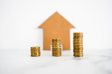 mortgage interests and property prices going up, growing stacks of coins with cardboard house