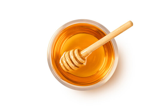 Glass bowl of honey with honey dipping on white background. Top view
