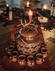 Big ceramic jar with indigenous painting on a red c carpet with candle in the background during sacred ceremony in Tulum
