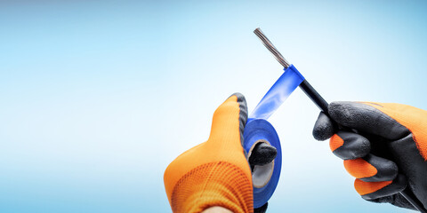 Electrician working with cables wiring. Hands of the electrician using  electrical tape with electricity wire. Banner with copy space.