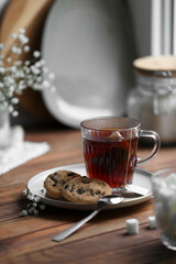 Cup of freshly brewed tea and delicious cookies on wooden table, space for text