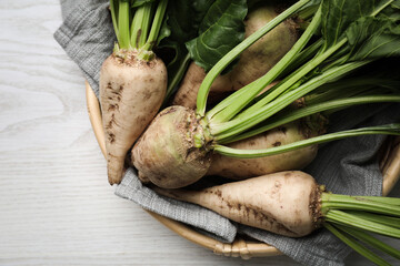 Basket with fresh sugar beets on white wooden table, top view