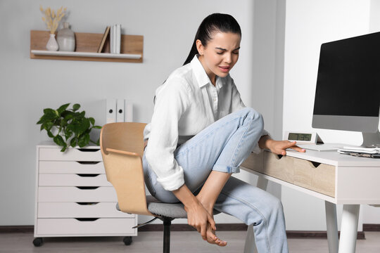 Young Woman Rubbing Sore Foot In Office