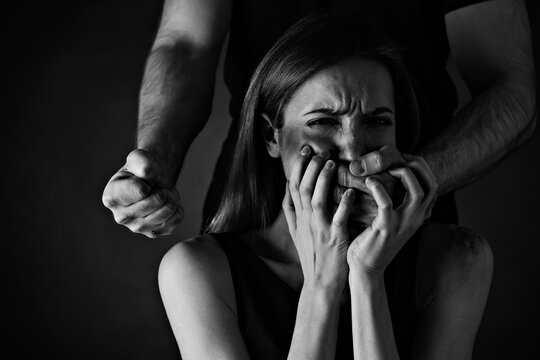 Man abusing scared woman on black background. Domestic violence
