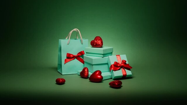 Many elegant teal blue gift boxes with red hearts isolated on beautiful Christmas emerald green background at night. Surprise gifts with jewelry for Birthday Anniversary, Christmas eve, New Year party