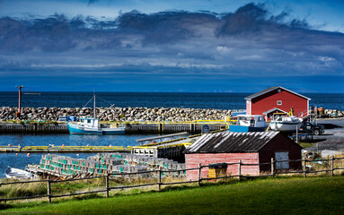 Fishing boats and lobster traps stacked on a dock at a small harbour inlet on the Canadian East Coast.
