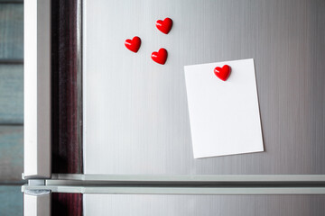 Empty paper sheet on refrigerator door. Note paper with magnetic heart. Valentine send text love...