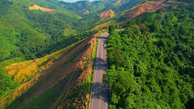 Drone fly over "Loi Fah Road", It is a beautiful country road and a famous tourist attraction. Nan, Thailand. high agricultural areas and tropical forest. green background in sunlight. travel concept
