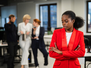 Young african woman is upset because of the ridicule of colleagues. Racial discrimination in the office. 