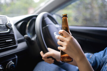 Woman drinking from a beer bottle while driving car, a concept of driving intoxicated.