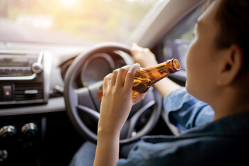 Close up of driver and drinking alcohol which Drunk young woman driving a car with a bottle of...