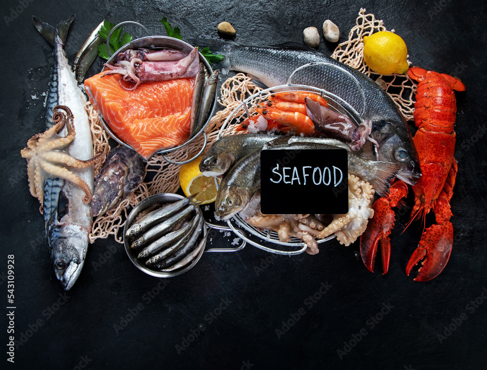 Sticker Fresh fish and seafood assortment on black background, fish market. Healthy diet eating concept. Top view., copy space.