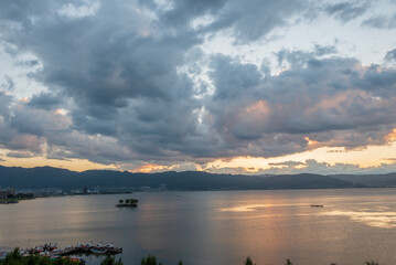 湖面と雲を照らしながら沈みゆく夕日