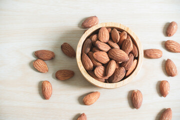 Almonds in brown wooden bowl on wooden table background. Top view.