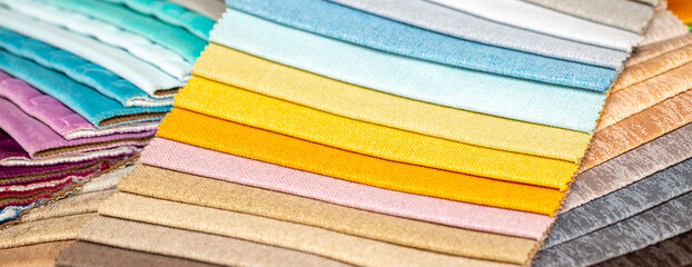 Fabric swatches in different colors are stacked for selection. A variety of shades of upholstery...