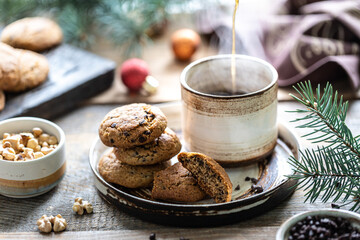 Homemade cookies with nuts and coffee in a ceramic cup on a wooden table with toys and Christmas tree branches