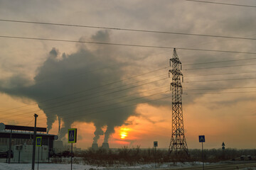 High power line and wires against the backdrop of sunset and smoke from a thermal power plant