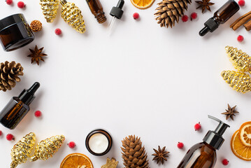 Fototapeta na wymiar Winter skin care concept. Top view photo of amber bottles christmas decor golden pine cone ornaments mistletoe berries dried citrus slices on isolated white background with copyspace in the middle