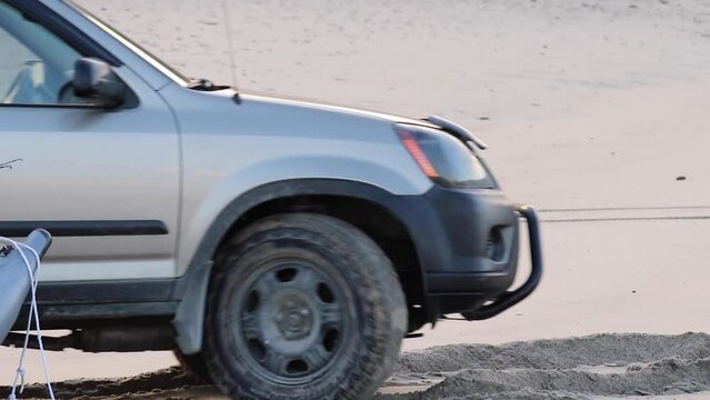 camera angle focused on car wheel backing up in the sand