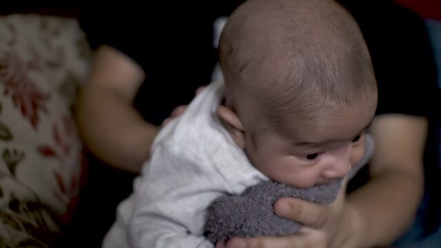 Father Gently Rubbing His 2 Month Old Son On The Back To Help Him Burp After Drinking Milk On His Lap. Locked Off