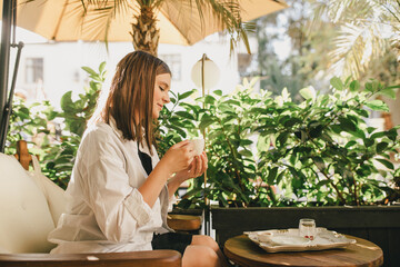 Woman enjoying traditional Turkish coffee sitting by wooden table.