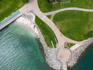 Top view of the Brant Street Pier on the rocky shore of Lake Ontario surrounded by a green field