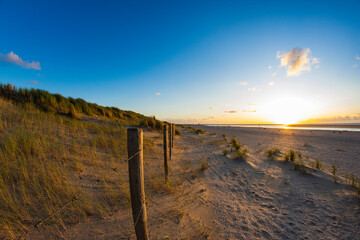 Footpath and fence on the seashore during a calm sunset in summer. Sea.