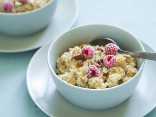 Quinoa porrige on tabletop. Two bowl wit quinoa milk porridge with berries and almond. Frozen raspberries in quinoa porrige